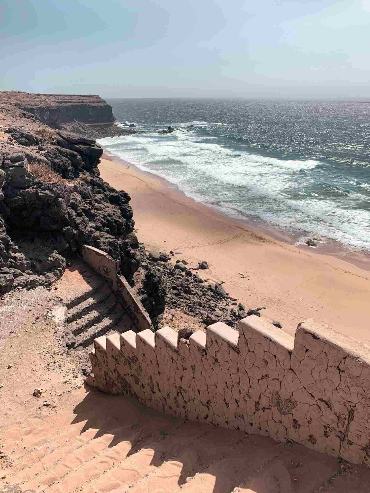 In den Fels gehauene Stufen über einem Sandstrand am Meer