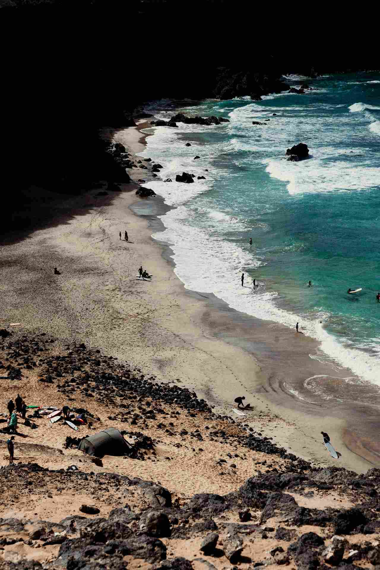 Blick von der Höhe auf Brandung und dunklen Sandstrand